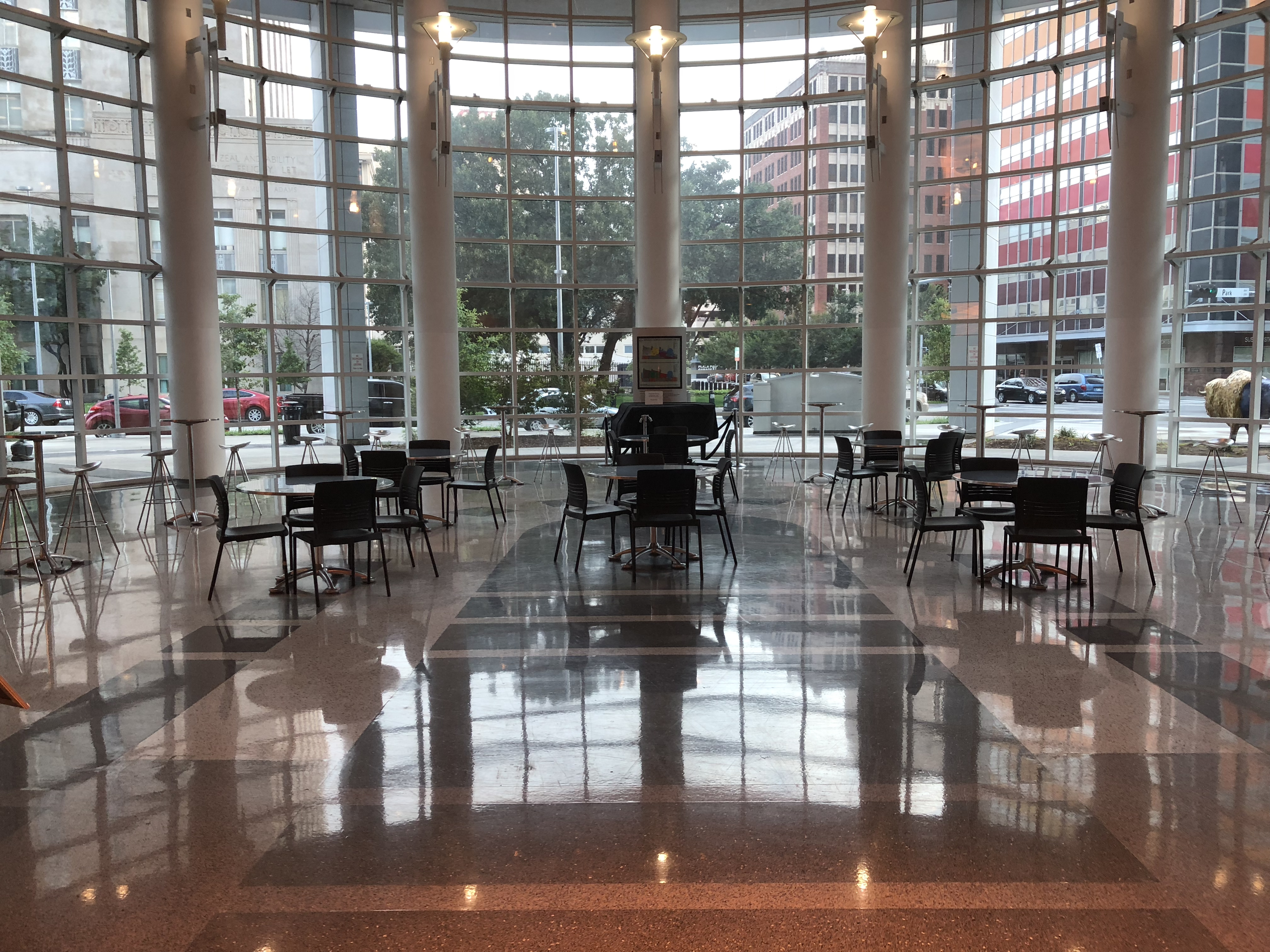Interior shot of the Atrium with polished floors, circular tables with chairs, and tall windows