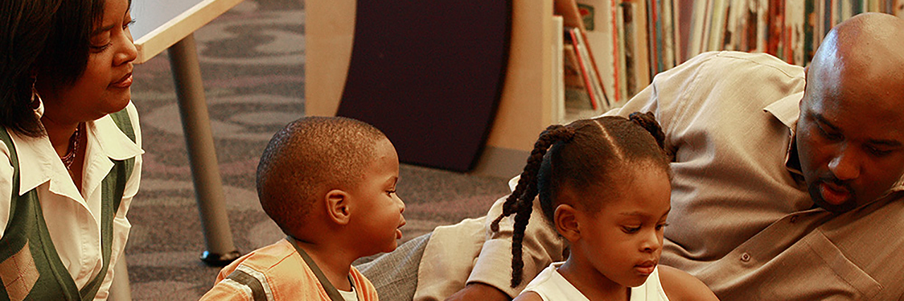 Husband and Wife helping their two children read