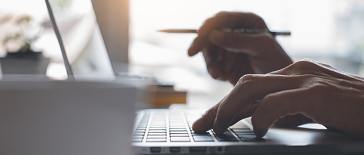 Person on laptop with pencil in hand