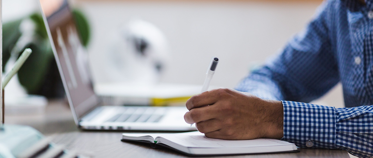 Special Collections header image Man doing research, taking notes from his laptop