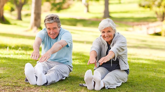 image of two elderly folks doing stretches in a nice green park