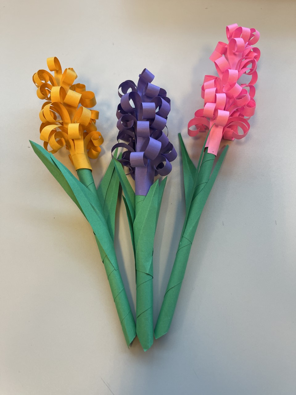 One yellow, one purple, and one pink paper hyacinth flowers. 