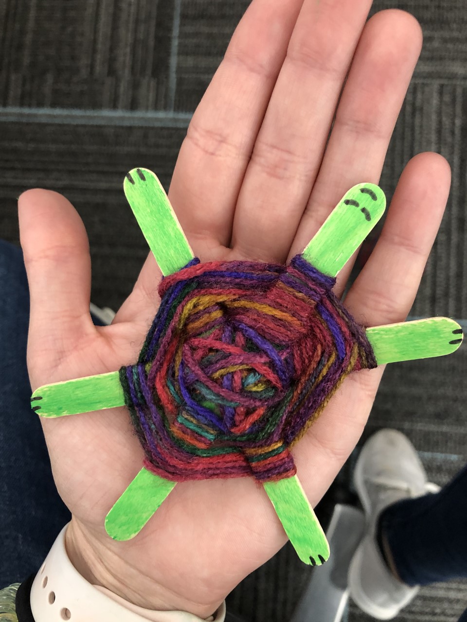 Picture of a hand holding a turtle made of craft sticks with a woven yarn shell
