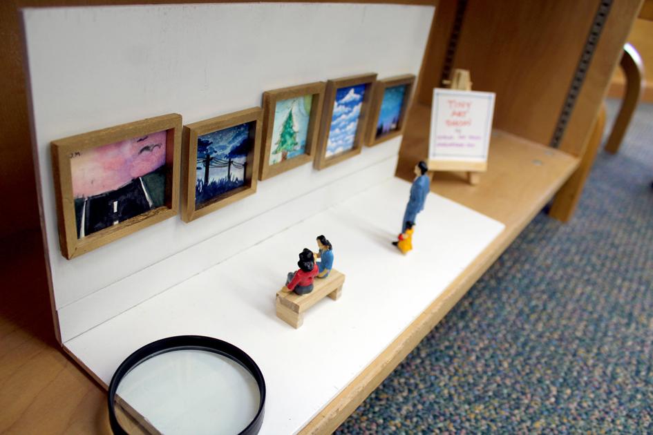 a miniature art gallery with tiny paintings and tiny people observing them
