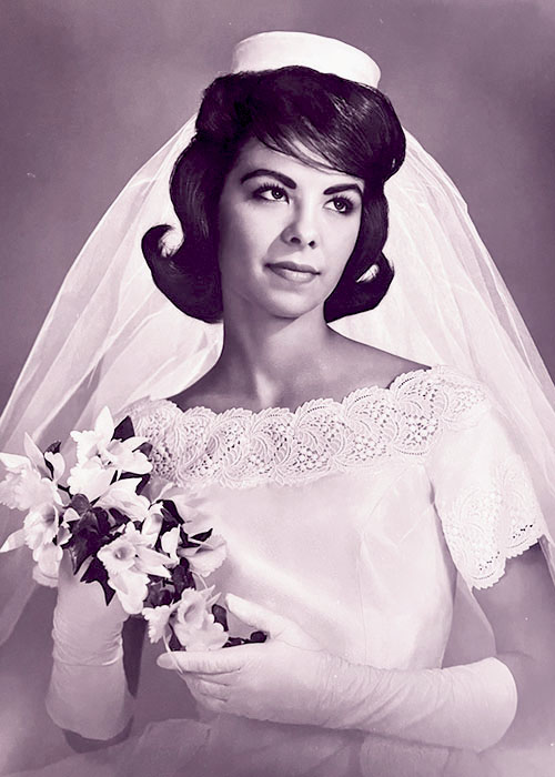 Photographic portrait of an unknown bride in her wedding dress with pillbox hat and veil, holding her bouquet.