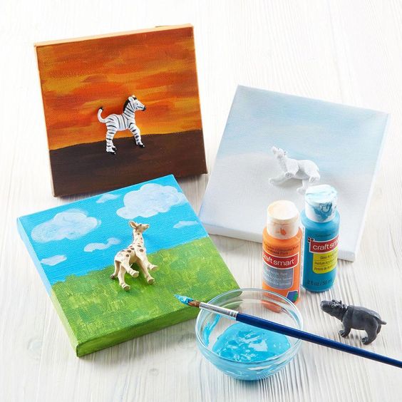 small canvas with painted landscapes and animal figurines glued into the image