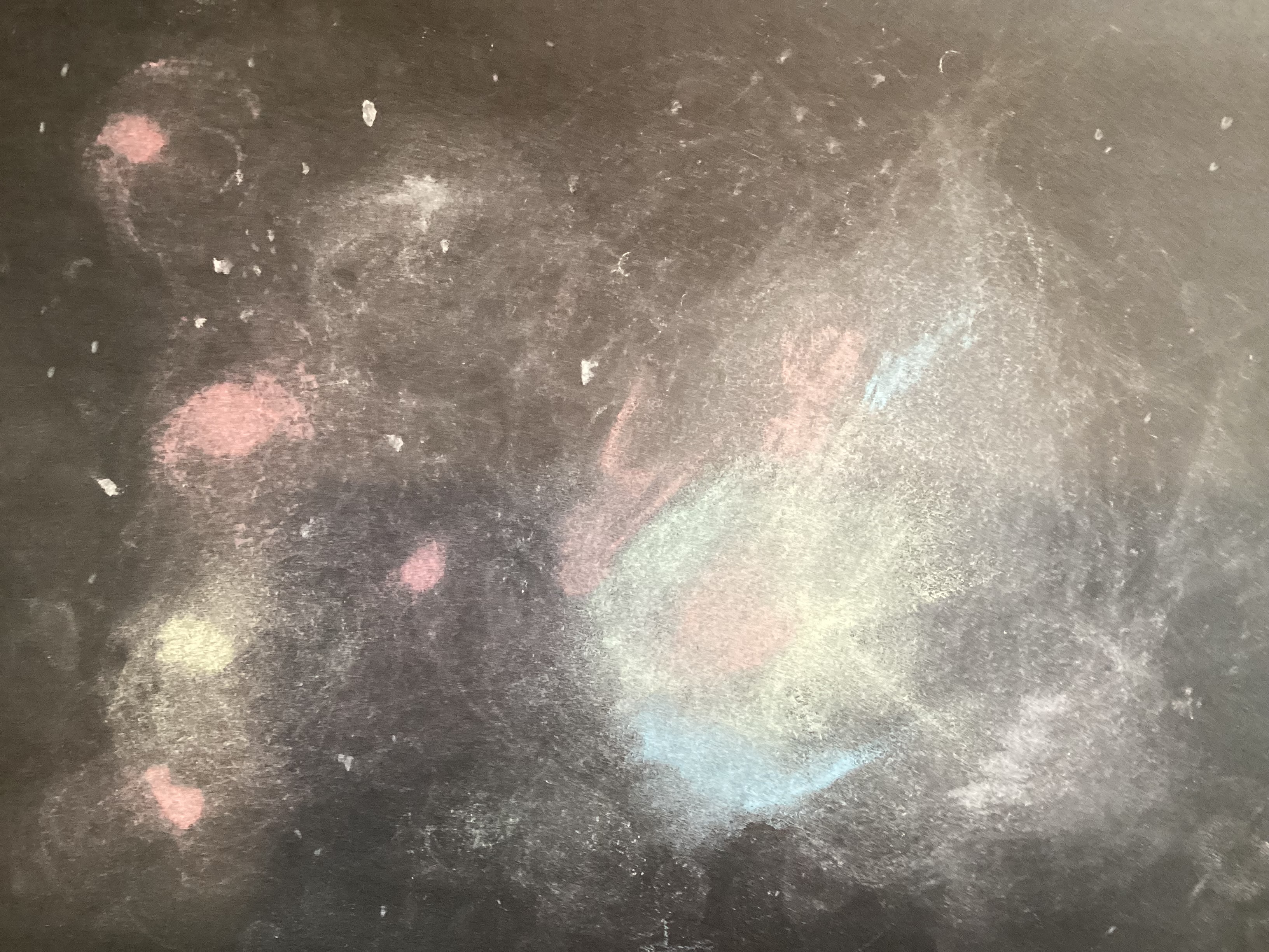 chalk smudges resembling a nebula in soft yellow, blue, and red on a black background