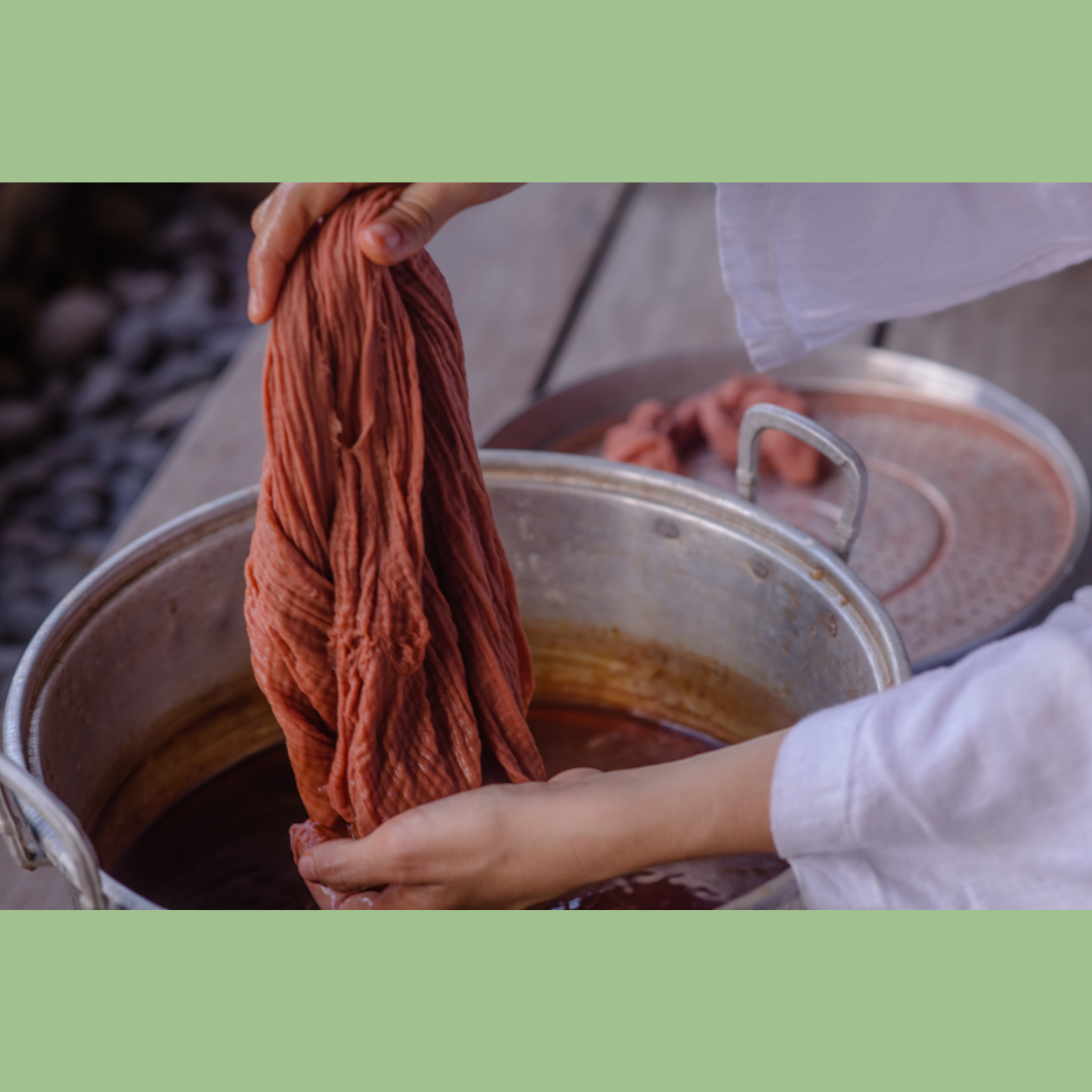 cloth being dipped in colored liquid to dye it.