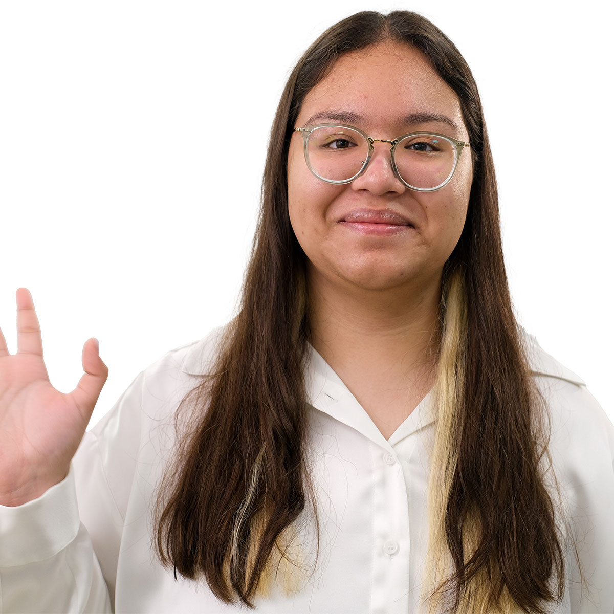 Teen girl with long brown hair and glasses looking at the camera and waving.