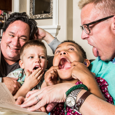 family reading and acting silly while holding book on a sofa