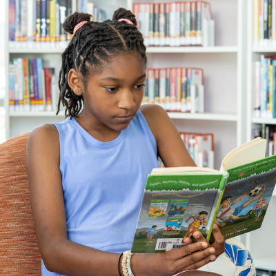 Child reading a book at the library 