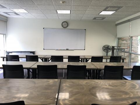 Classroom D with tables and chairs and white board at front of room