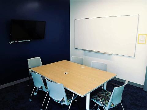 study room with 6 chairs a tv and whiteboard