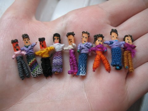 An assortment of Guatemalan worry dolls made from wire, paper and cotton fabric and thread, with hand-drawn faces.