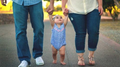 small child holding hands with mom and dad