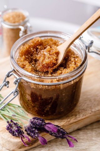 close up of sugar scrub, flowers, and wooden spoon