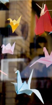 Origami cranes in various colors hanging from individual strings