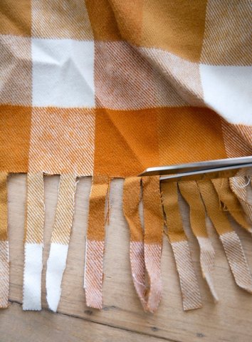 Scissors cutting the fringe of a felt blanket