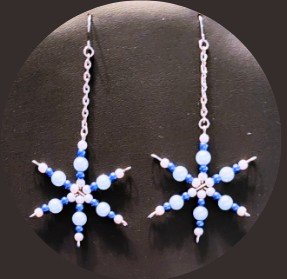 A pair of earrings using blue, white, and silver beads in the shape of a snowflake. 
