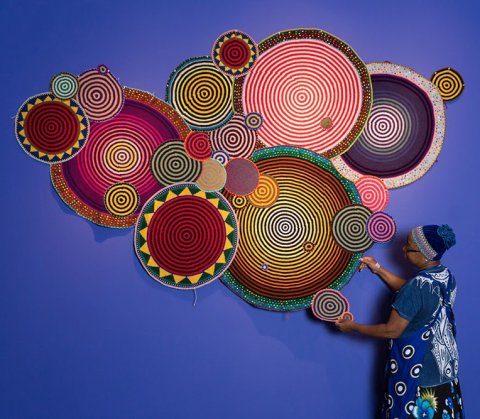Artist Xenobia Bailey hangs her crocheted mandalas on a blue wall