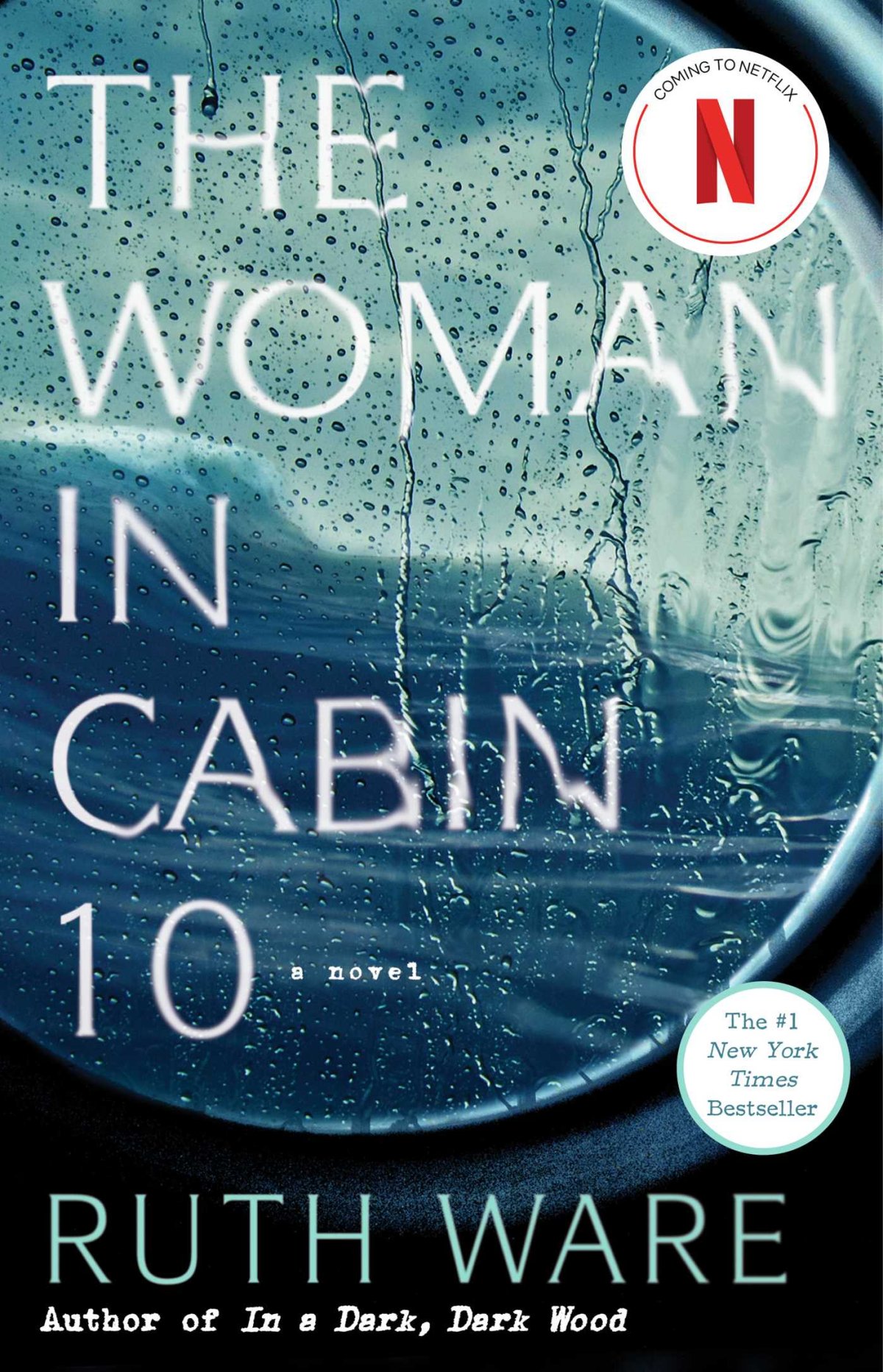 A cabin window looking out to a stormy sea. Rain is splashed on the window. 