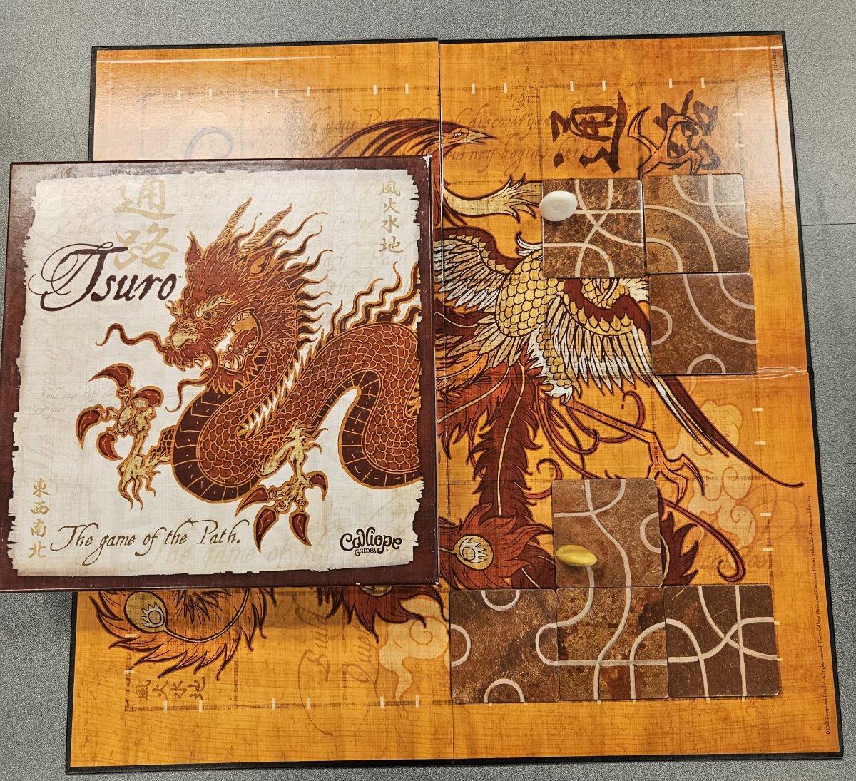 board game called Tsuro presented with lined tiles laid out on the board with small dragon tokens