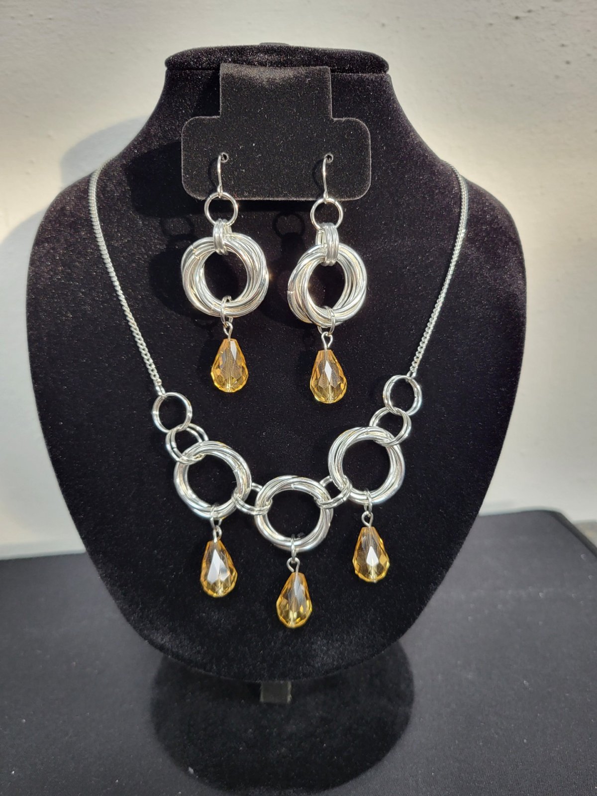 Chainmail Earrings and Necklace with beads, on a jewelry stand.