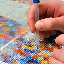 a close up of hand and pick tool  showing someone diamond painting a picture