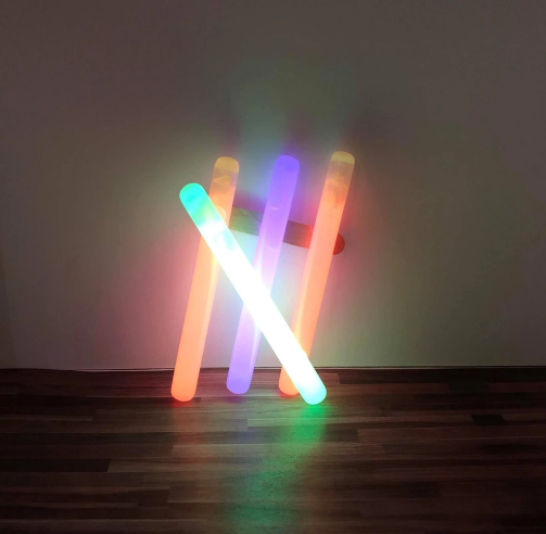 Art by Dan Flavin featuring Neon light rods in green, orange and purple
